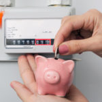 putting a quarter into a piggy bank in front of an energy meter