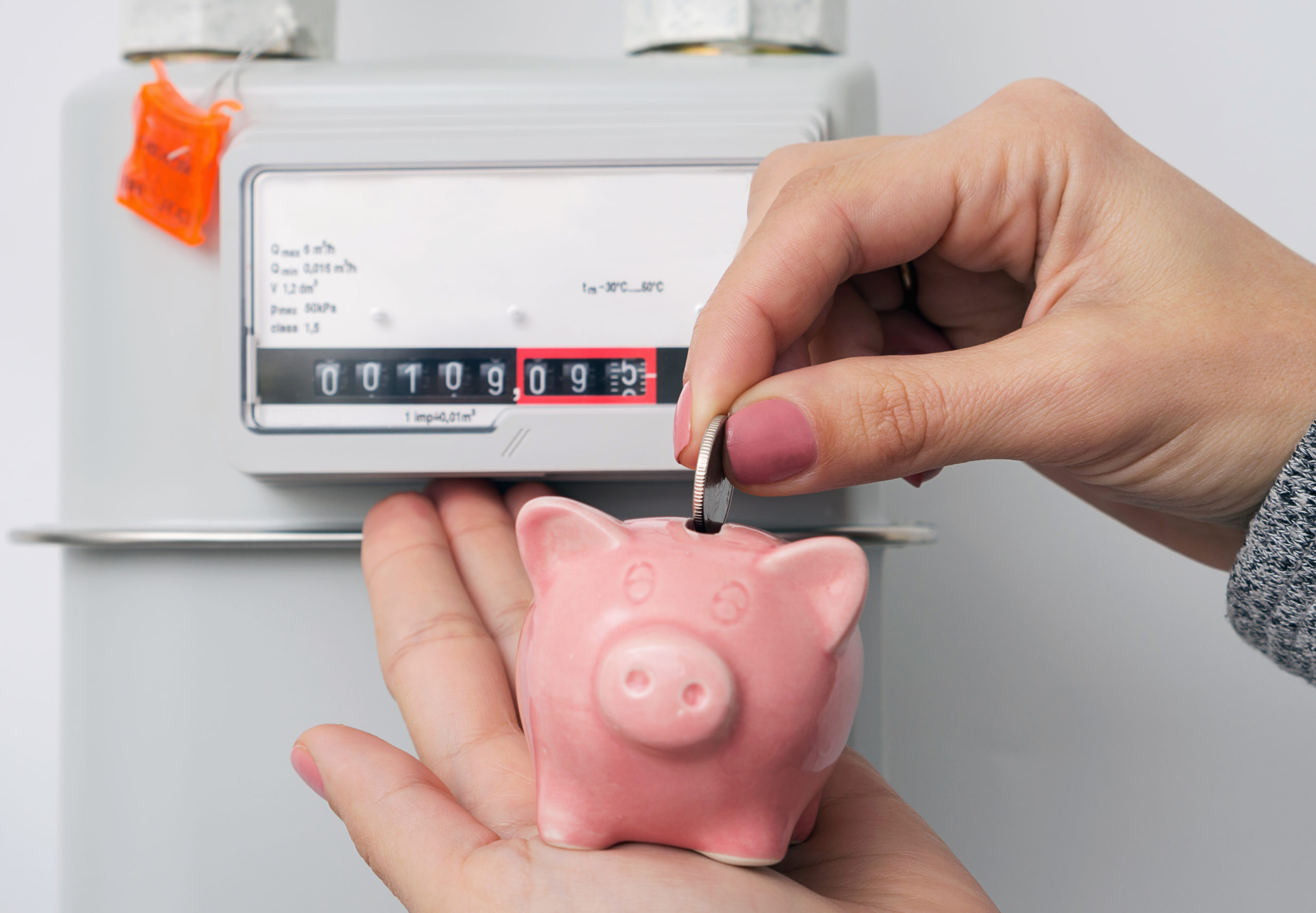 putting a quarter into a piggy bank in front of an energy meter