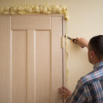 a man cutting sealing foam around a door
