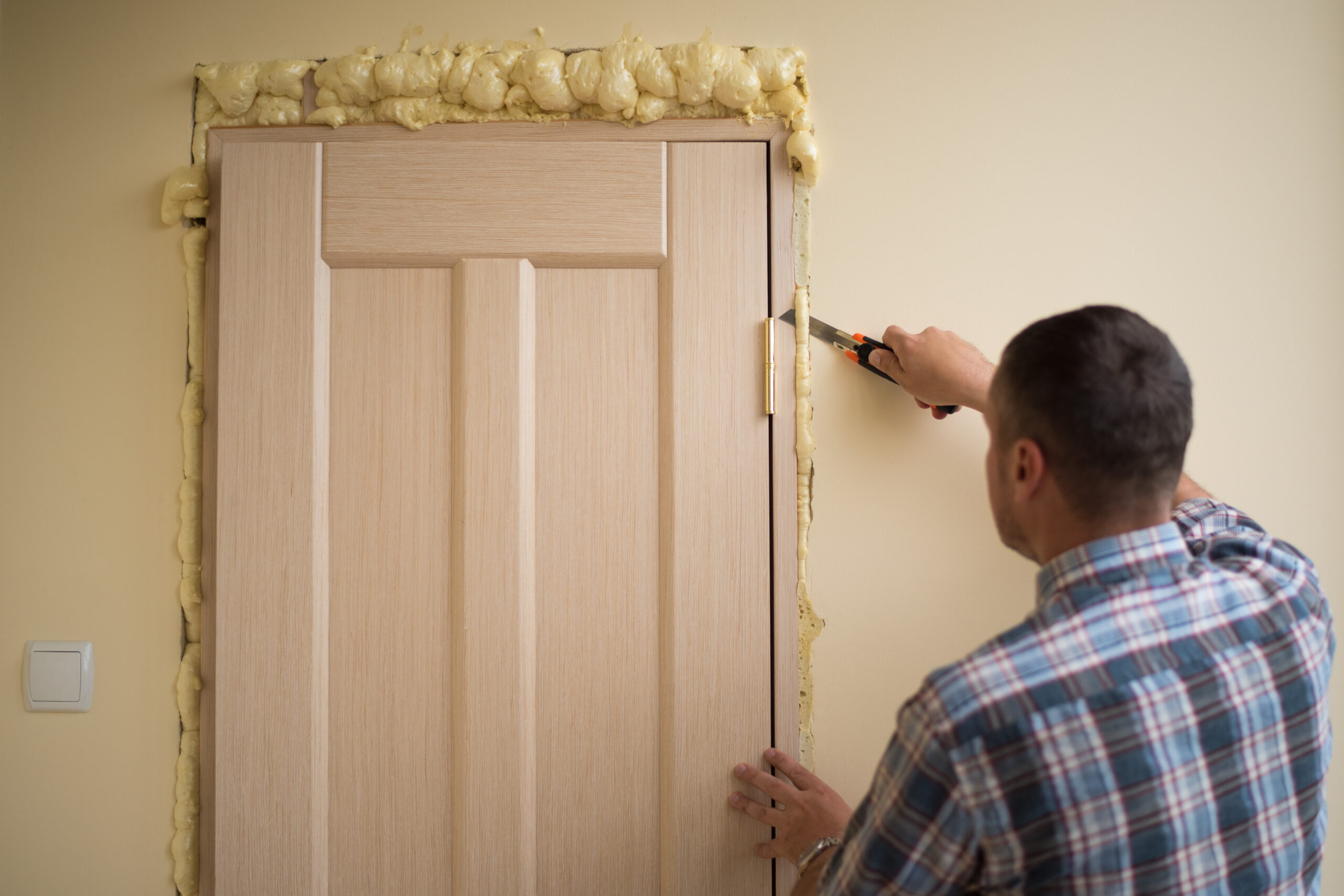 a man cutting sealing foam around a door