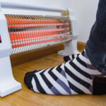 feet with black and white striped socks warming up next to a space heater