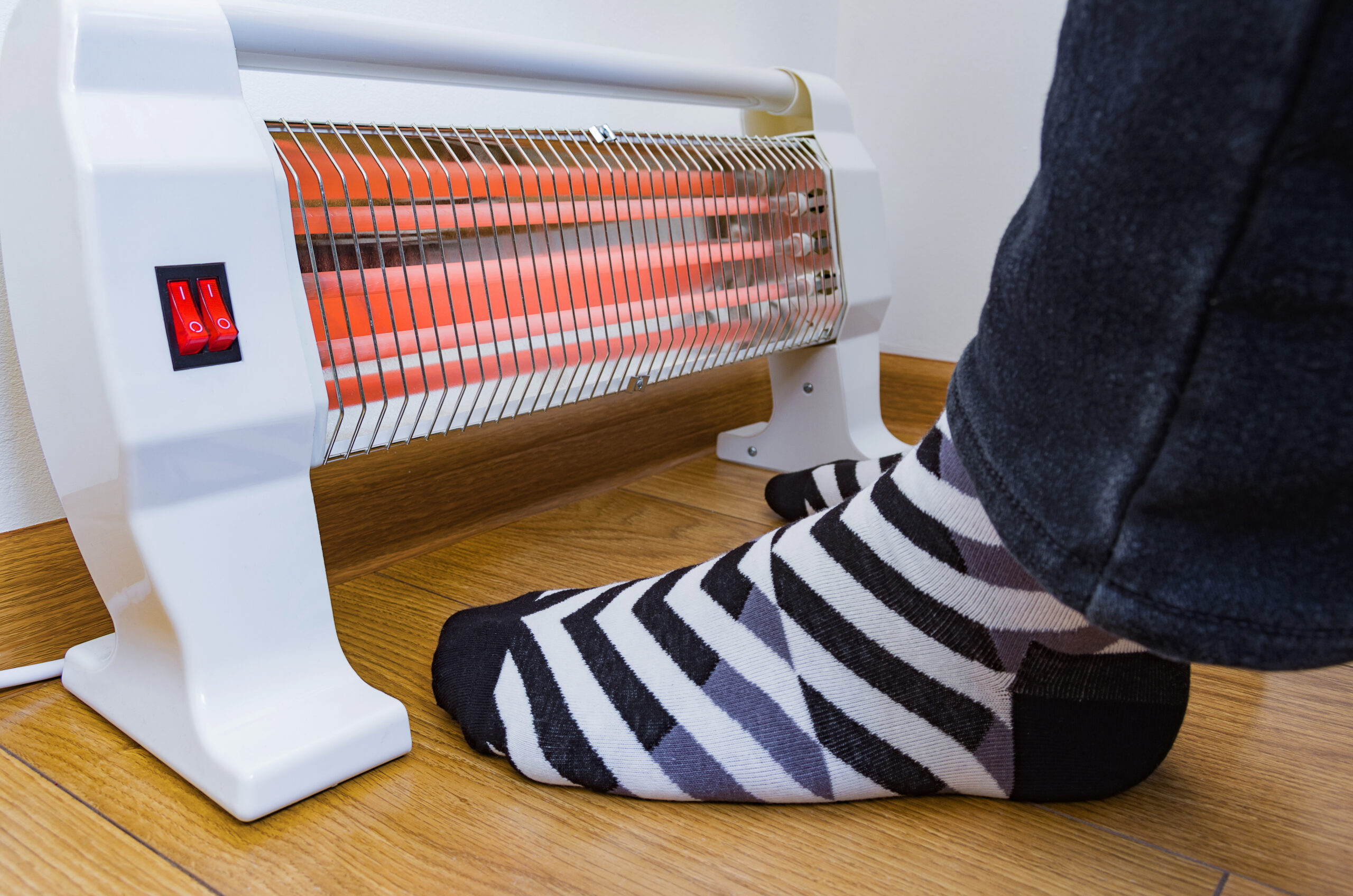 feet with black and white striped socks warming up next to a space heater