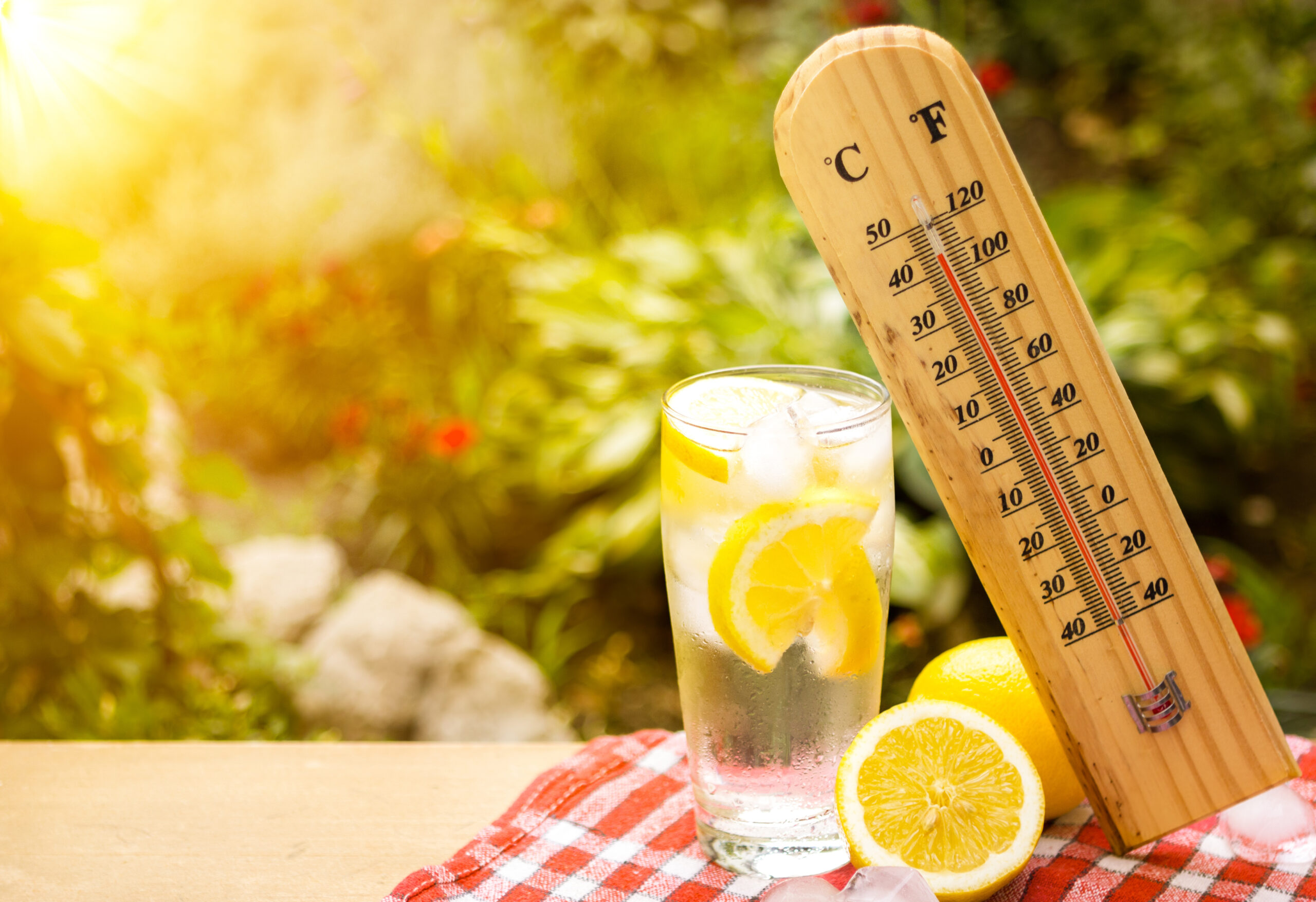 thermometer shows a high temperature next to lemon water during heat wave