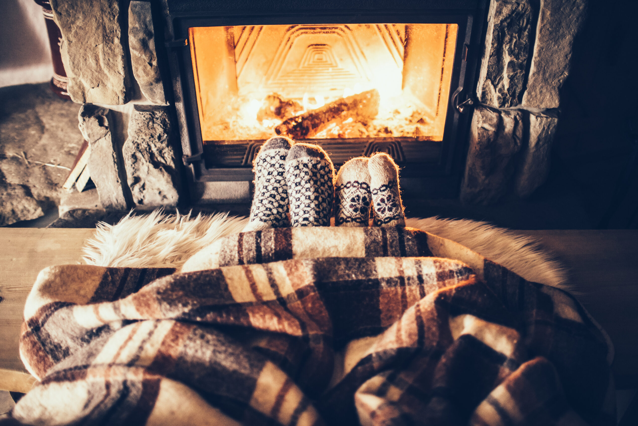 two pairs of feet warming in front of a fireplace