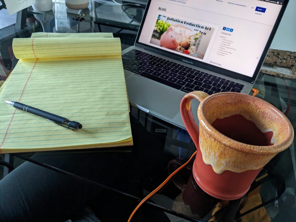 yellow legal pad, coffee mug, and laptop showing the Energy Efficiency Experts blog page