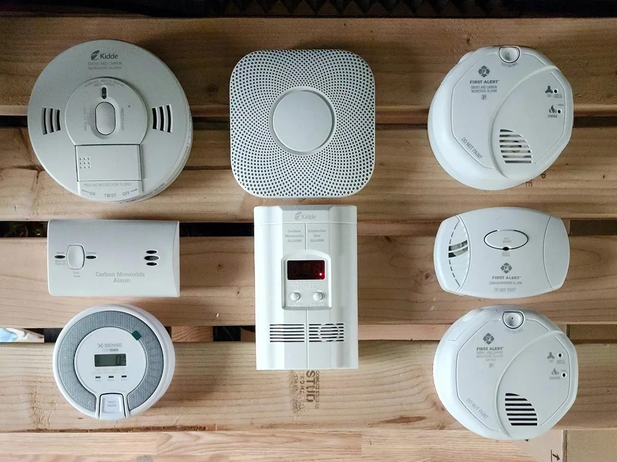 8 different types of carbon monoxide detectors on a wooden slat background